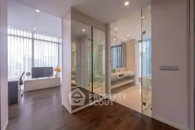 Modern apartment interior with glass partitions and wooden flooring, featuring a stylish living area and bathroom.