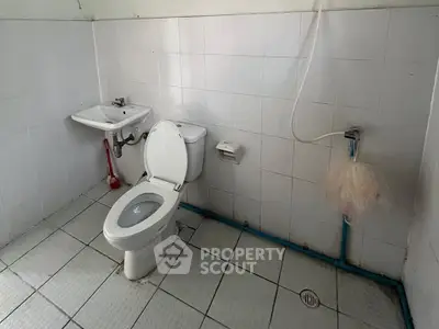 Simple bathroom with white tiles and basic fixtures, ideal for budget-friendly renovations.