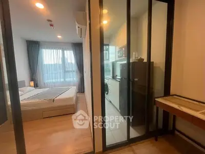 Modern apartment with glass partitioned bedroom and compact kitchen area.