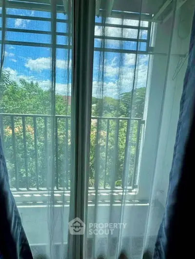 Charming balcony view with lush greenery and blue sky, perfect for relaxation.