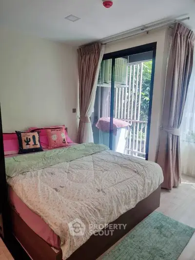 Cozy bedroom with large window and balcony access, featuring stylish curtains and a comfortable bed.