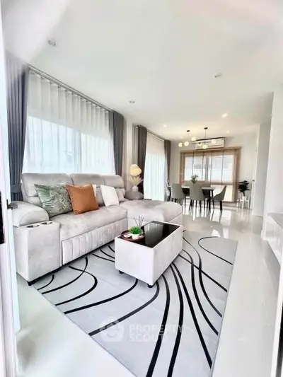 Spacious modern living room with elegant decor and open dining area, featuring large windows and stylish furnishings.