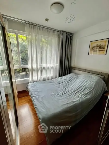 Cozy bedroom with large window and wooden flooring, perfect for natural light lovers.