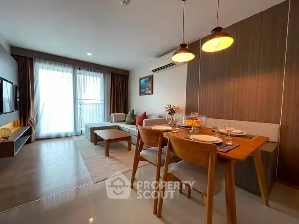 Modern living room with dining area, stylish decor, and natural light from large windows.