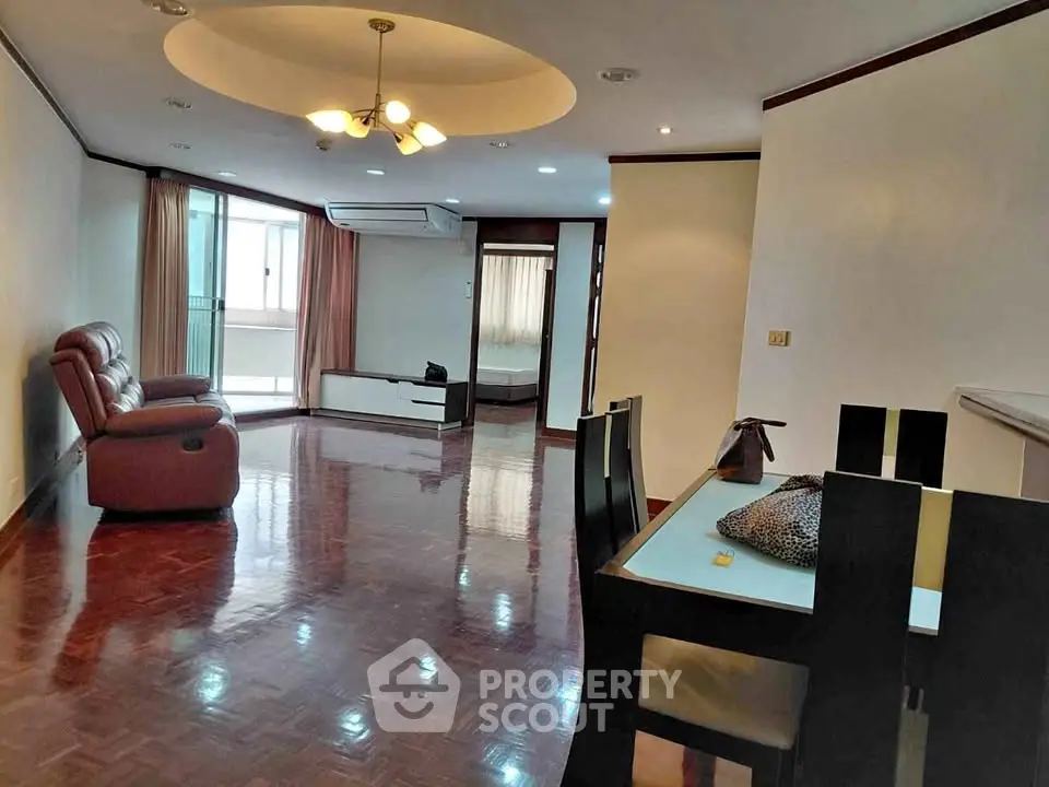 Spacious living room with elegant lighting and polished wooden floors in a modern apartment.