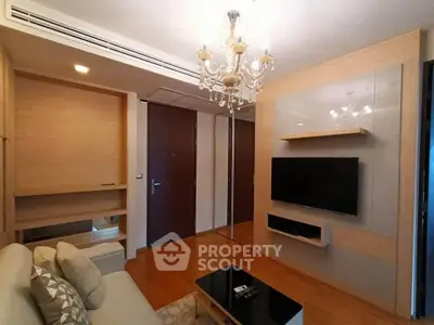 Elegant living room with chandelier and modern TV setup in a cozy apartment.
