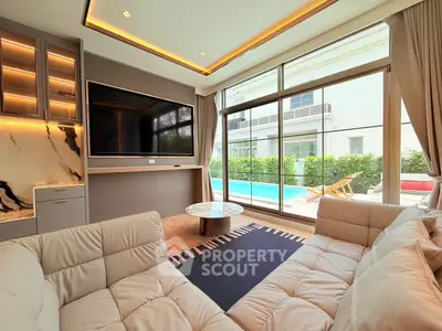 Luxurious living room with pool view, modern decor, and large TV, perfect for relaxation and entertainment.