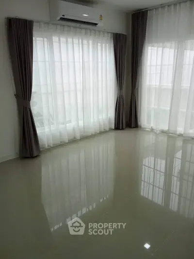 Spacious empty room with large windows and elegant curtains, perfect for customization.