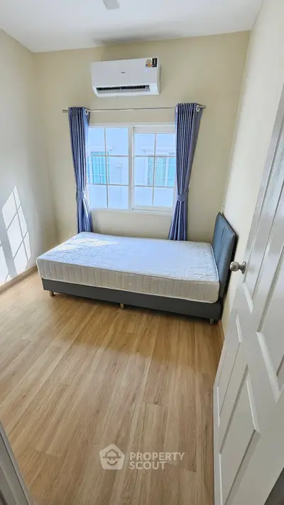 Cozy bedroom with natural light, featuring a single bed and air conditioning, perfect for a comfortable living space.