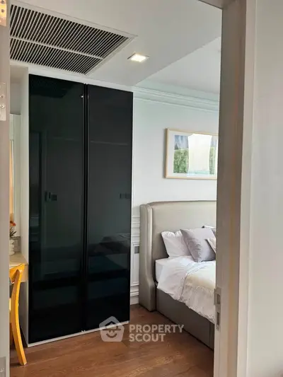 Modern bedroom with sleek black wardrobe and cozy bed in stylish apartment.