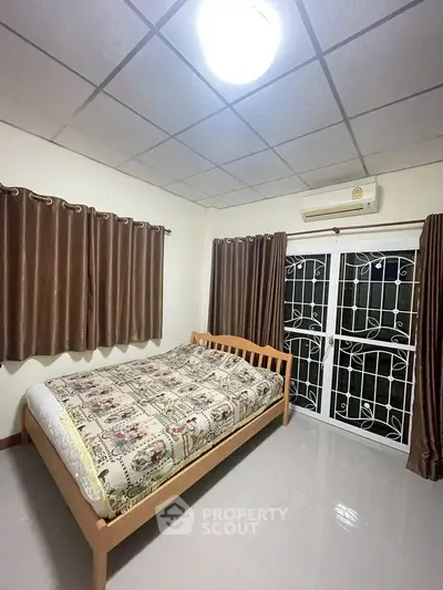 Cozy bedroom with wooden bed frame and large window with curtains.