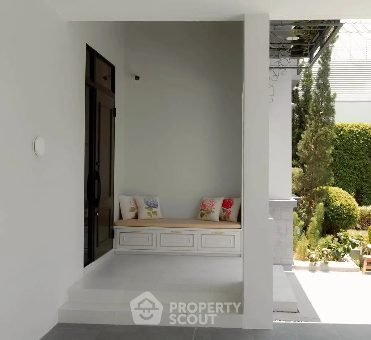 Charming entrance with cozy seating and lush garden view, perfect for relaxation and welcoming guests.