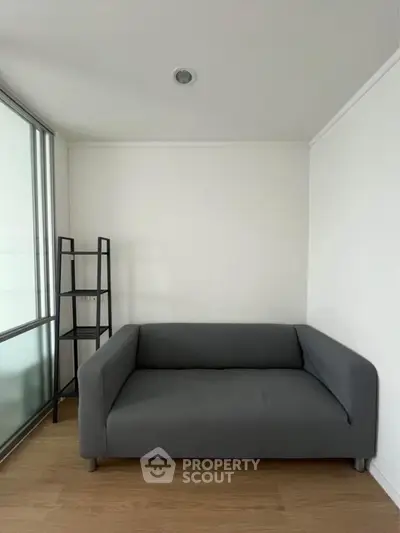 Modern minimalist living room with sleek gray sofa and glass partition.