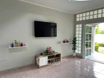 Bright living room with modern TV setup and garden view, perfect for relaxation.