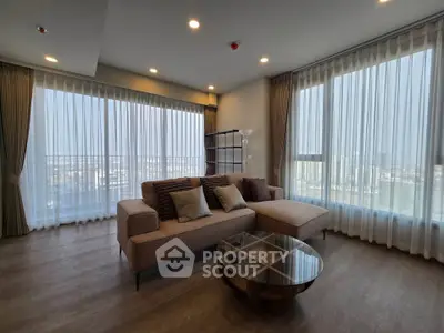 Spacious modern living room with large windows and stylish furniture in a high-rise apartment.