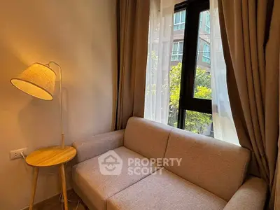 Cozy living room with a modern sofa and floor lamp by a large window with curtains.