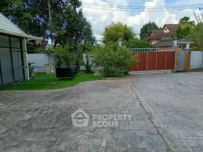 Spacious driveway with gated entrance and lush greenery in a serene neighborhood.