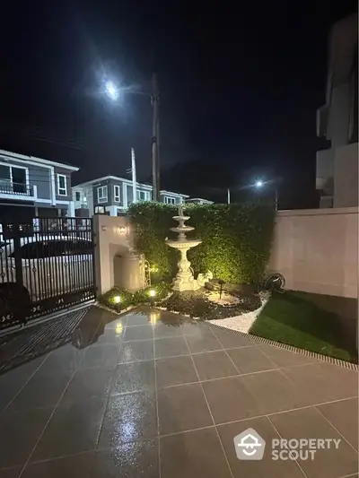 Charming night view of a modern garden with elegant fountain and ambient lighting.