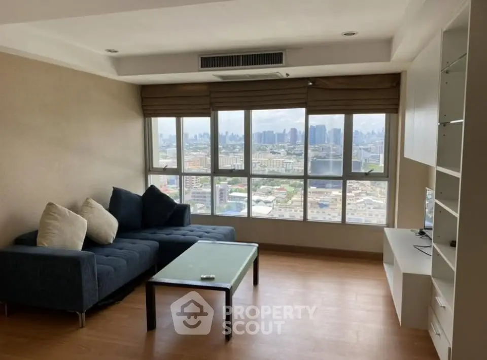 Spacious living room with large windows offering stunning city views, modern sofa, and sleek entertainment unit.