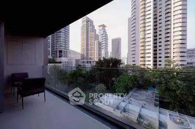 Modern balcony with glass railing offering stunning cityscape views of high-rise buildings.