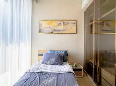Modern bedroom with stylish decor and ample natural light, featuring a single bed and mirrored wardrobe.