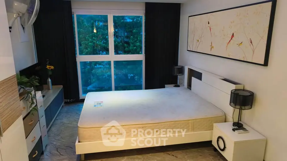 Spacious bedroom with large window and modern decor, offering serene views and ample natural light.