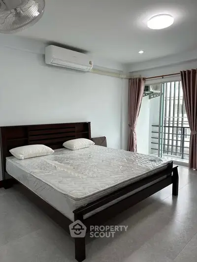 Spacious bedroom with modern bed and natural light from large window.