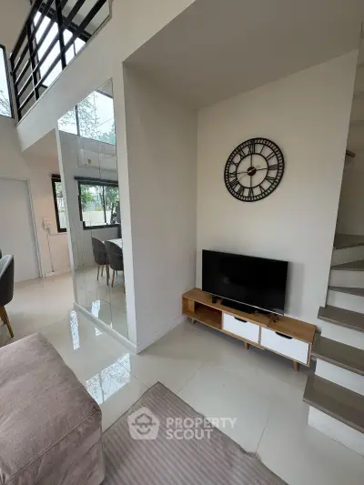 Modern living room with stylish decor and open layout, featuring a wall clock and sleek TV stand.