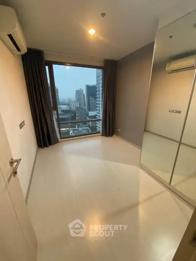 Spacious bedroom with large window offering city view in modern apartment