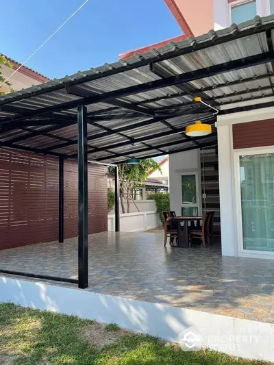 Charming outdoor patio with modern roofing and cozy dining area in a serene residential setting.