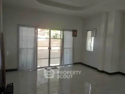 Spacious living room with large windows and tiled flooring, perfect for natural light.