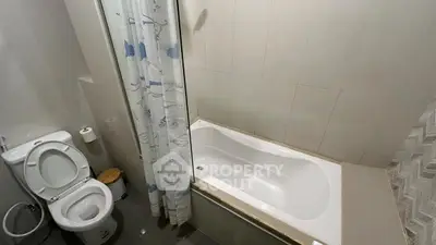 Modern bathroom with bathtub and shower curtain in a compact space.