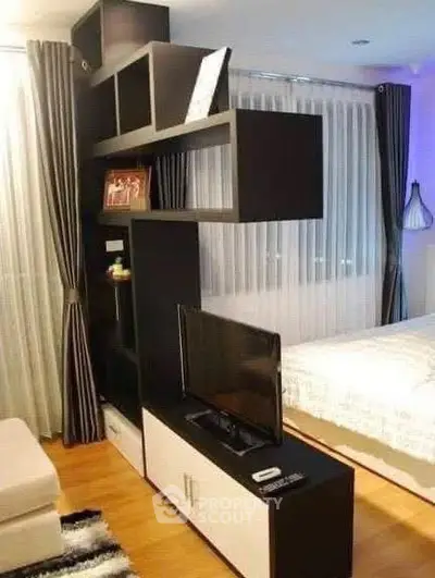 Modern living room with stylish black shelving unit and cozy bedroom view.