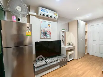 Modern living room with sleek furniture and appliances, featuring a TV and air conditioning.