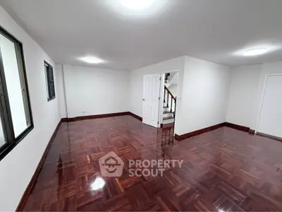 Spacious empty room with polished wooden floors and white walls, ideal for customization.