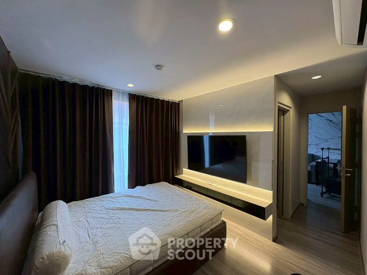 Modern bedroom with sleek design and large TV, featuring cozy lighting and elegant decor.