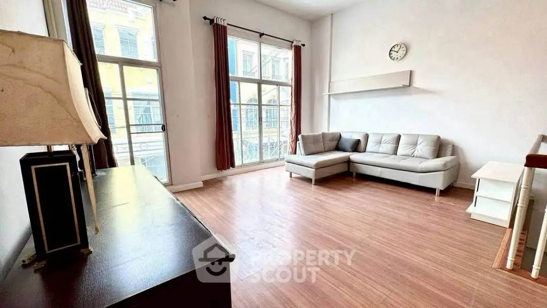 Spacious living room with large windows and modern furniture in a bright apartment.