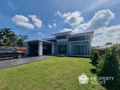 Modern single-story house with spacious lawn and driveway under clear blue sky.