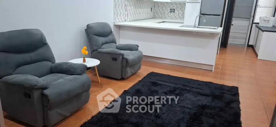 Modern open-layout living room with cozy recliners and sleek kitchen area.