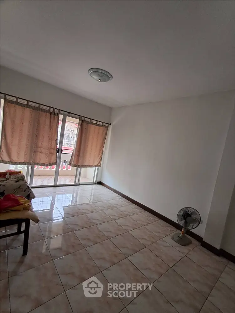 Spacious living room with tiled flooring and large windows for natural light.
