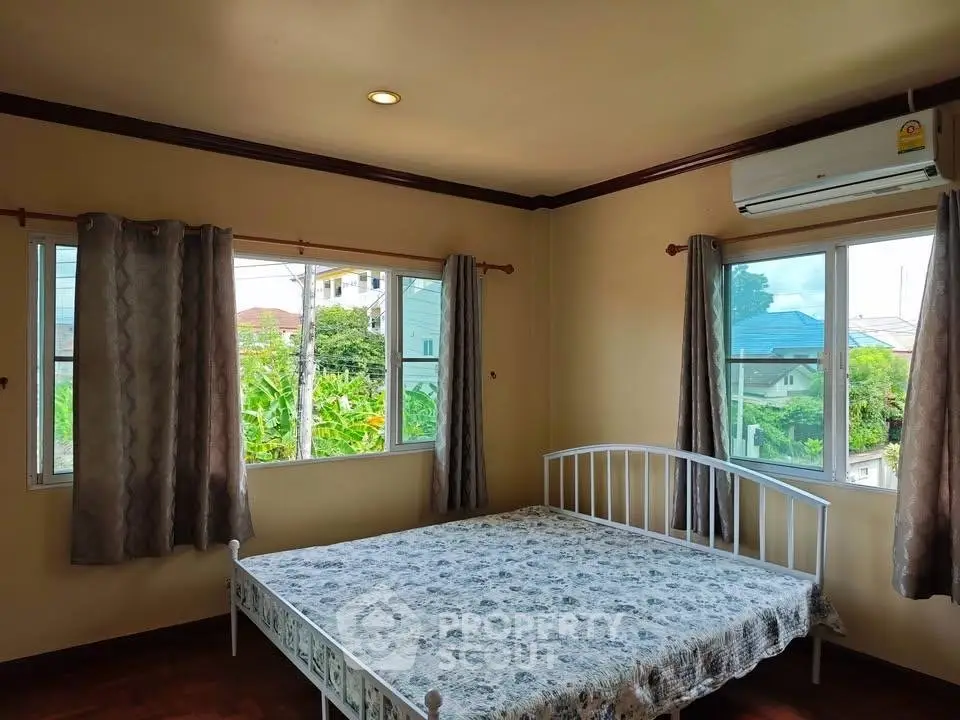 Cozy bedroom with large windows and air conditioning, offering a serene view.