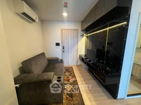 Modern living room with sleek black entertainment unit and cozy gray sofa.