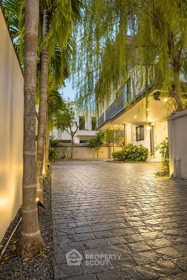 Charming modern home exterior with lush garden and elegant driveway lighting.