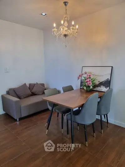 Elegant dining area with chandelier and modern furniture in cozy apartment.