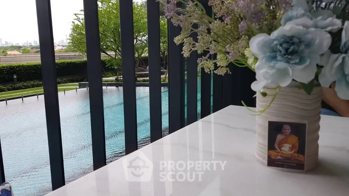 Luxurious poolside view with elegant floral arrangement on marble table, perfect for relaxation.