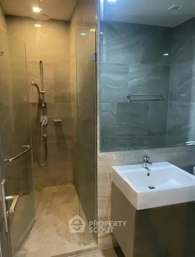 Modern bathroom with glass shower and sleek sink in contemporary design.