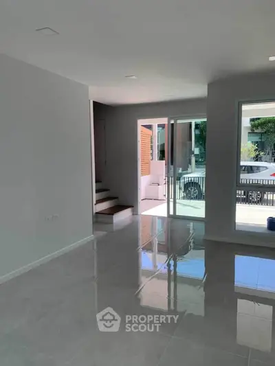 Spacious modern living room with glossy tiled floors and large windows for natural light.