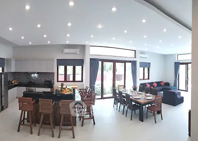 Spacious open-plan living room and kitchen with modern decor and ample natural light.