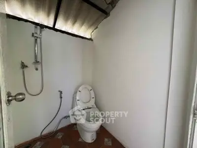 Minimalist bathroom with open ceiling and shower setup