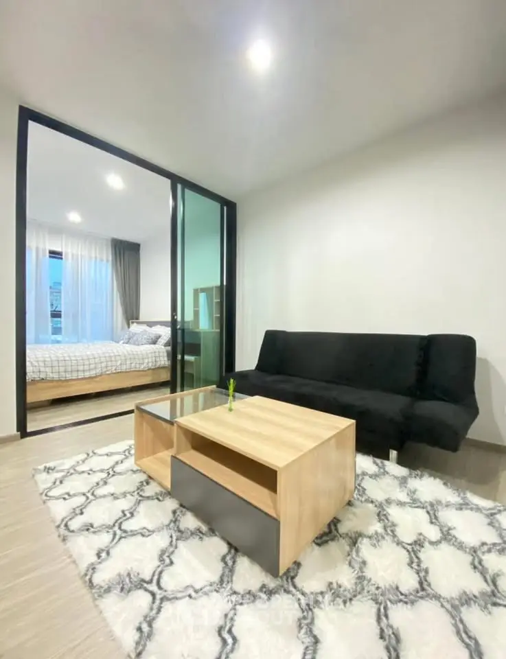 Modern living room with cozy rug and view into stylish bedroom